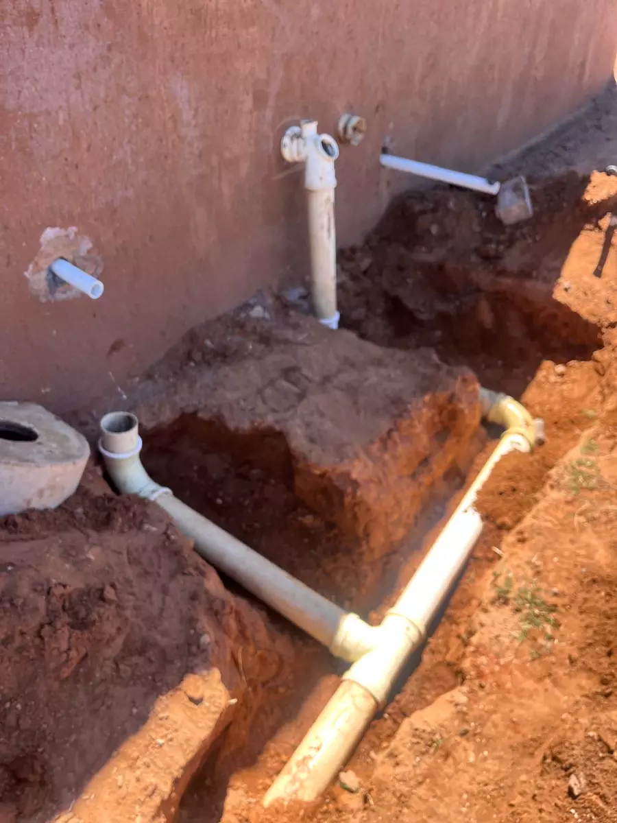 Plumbing pipes laid in a trench next to a wall